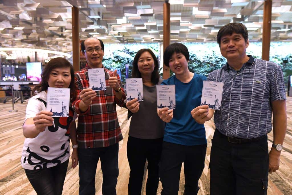 Passengers of flight SQ22, Singapore Airlines' inaugural non-stop flight to New York pose with souvenir cards after their their check-in at Changi.
