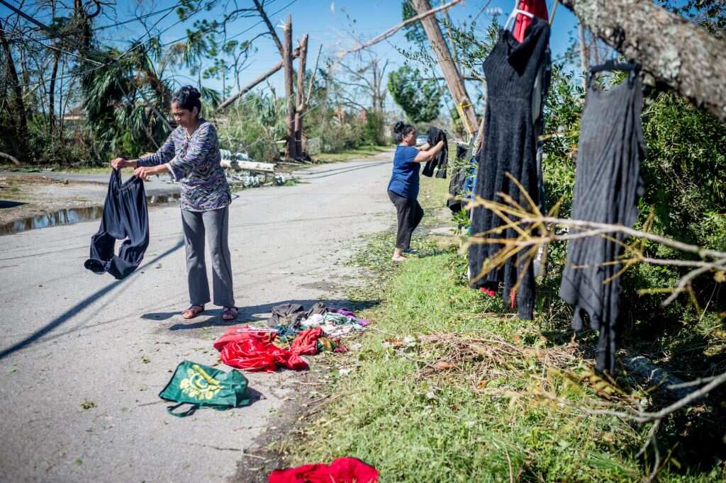 A family hangs clothes to dry outside a downed tree by their house in Panama City, Florida.