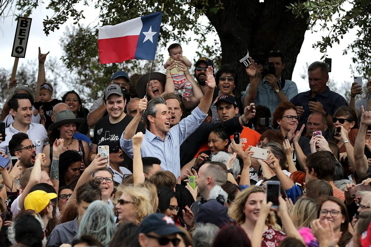 Beto O'Rourke holds a Texas flag with supporters during a campaign rally in Mueller Lake Park.