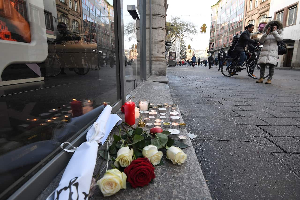 Flowers and candles are seen on the pavement the day after a deadly shooting in central Strasbourg.