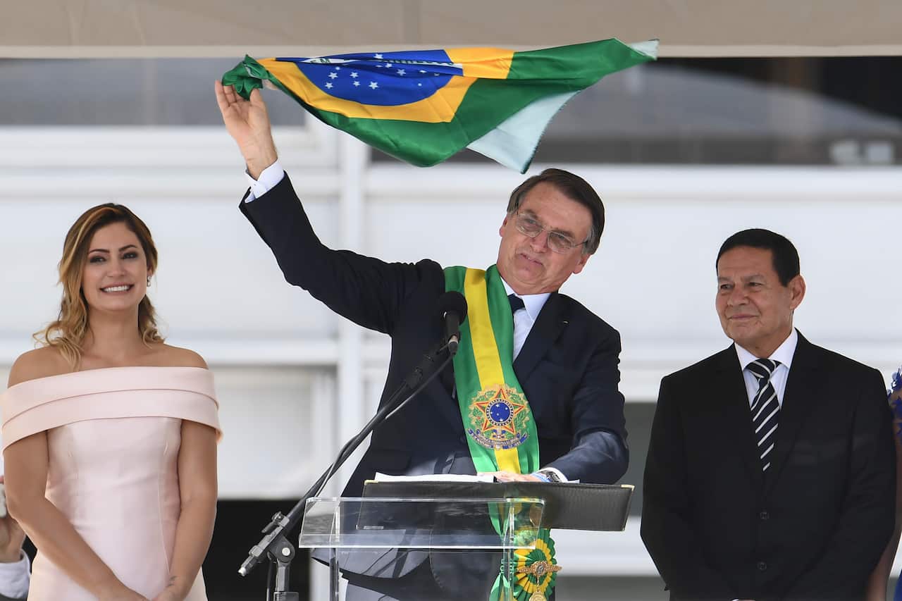 President Jair Bolsonaro addressing supporters flanked by First Lady Michelle Bolsonaro and Vice-President Hamilton Mourao.