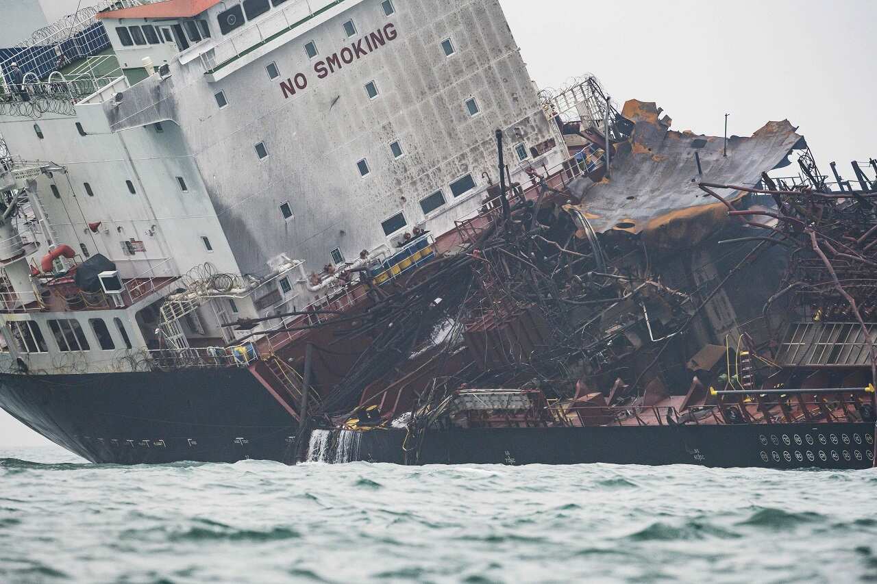 The damaged oil tanker is seen tilting to one side.