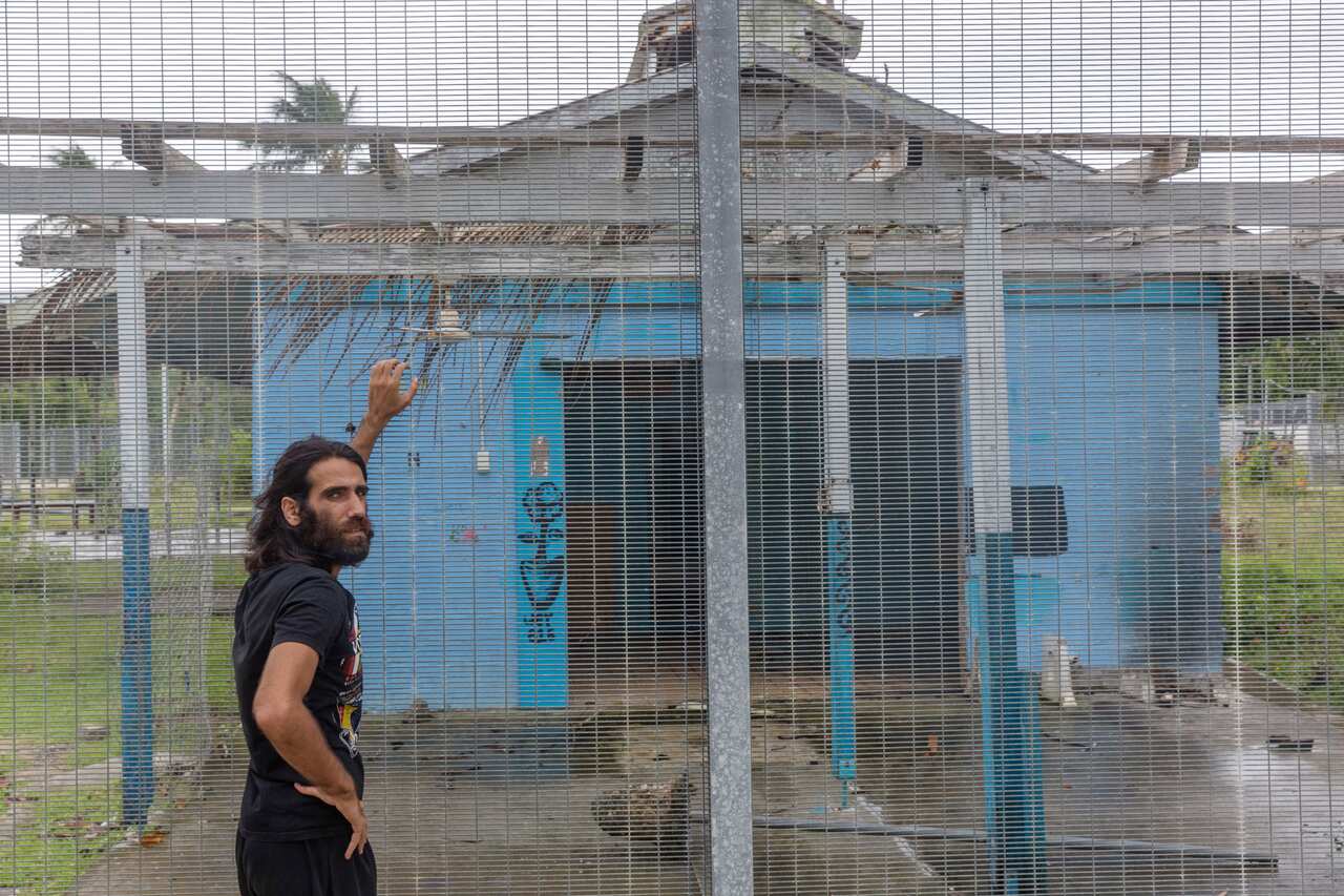 Asylum seeker Behrouz Boochani stands outside the  abandoned naval base on Manus Island where he and others were housed.