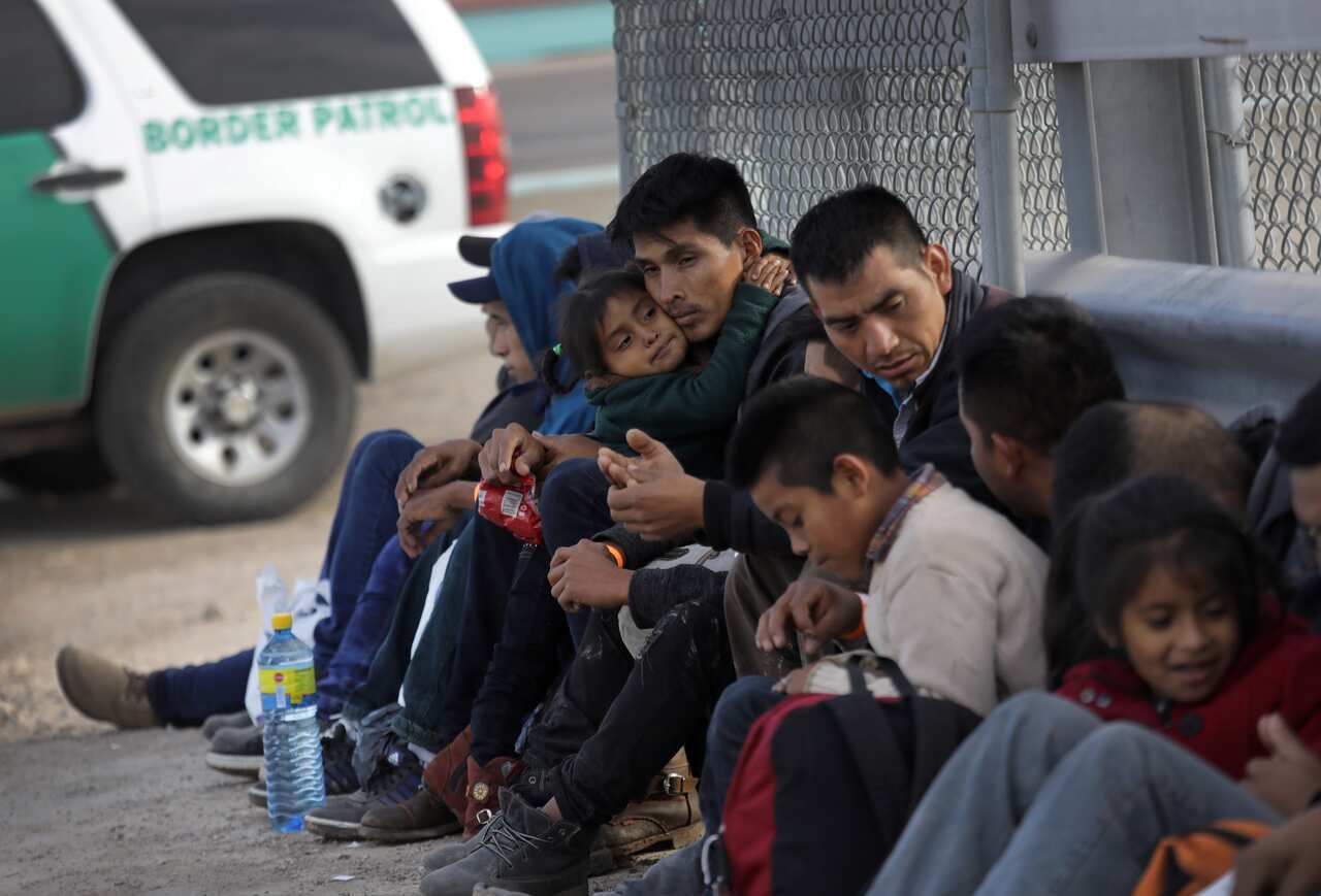 Central American migrants wait to be taken into custody after crossing into the United States from Mexico.