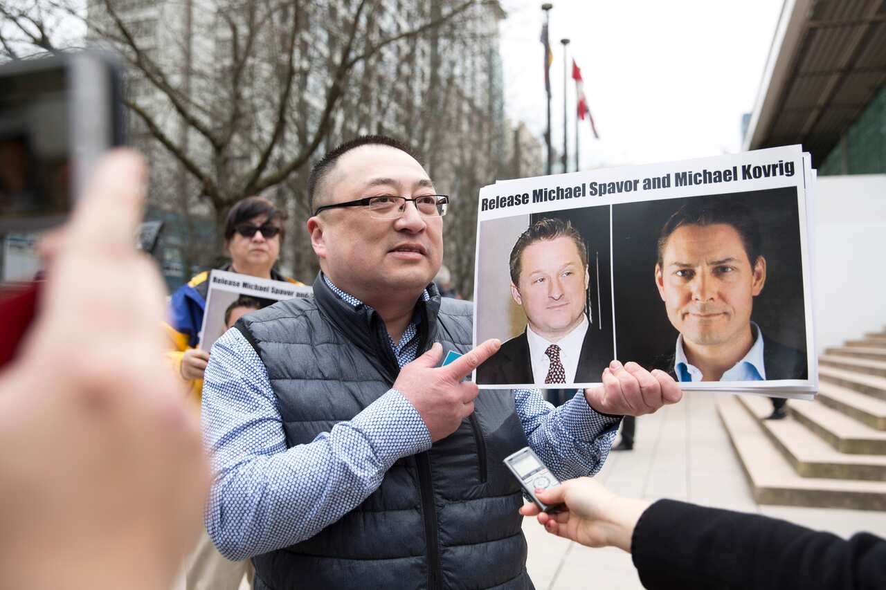 Louis Huang of Vancouver Freedom and Democracy for China holds photos of Canadians Michael Spavor and Michael Kovrig.