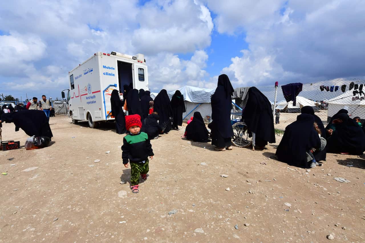 Veiled women living in al-Hol camp which houses relatives of Islamic State (IS) group members, queue to receive medical aid.