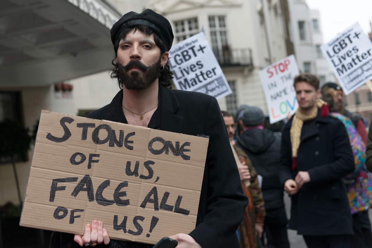A protester is seen holding a placard that says Stone one of