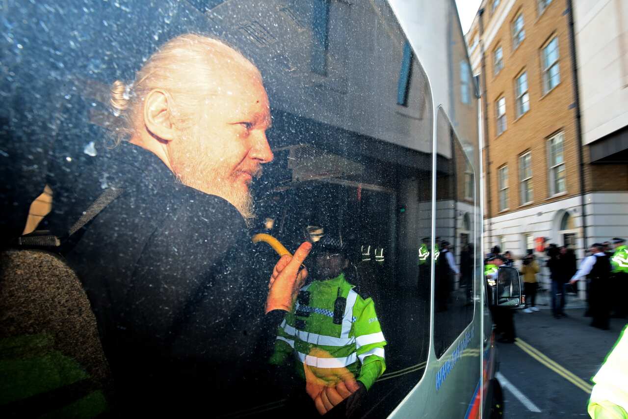 Julian Assange gestures to the media from a police vehicle on his arrival at Westminster Magistrates court.