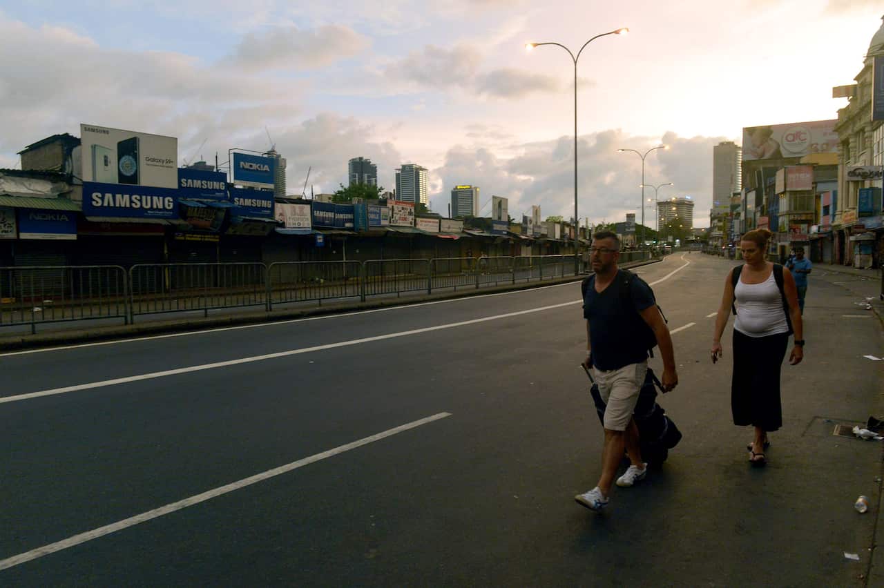 Tourists walk along the road after the Sri Lanka Police curfew in Colombo on April 21, 2019.