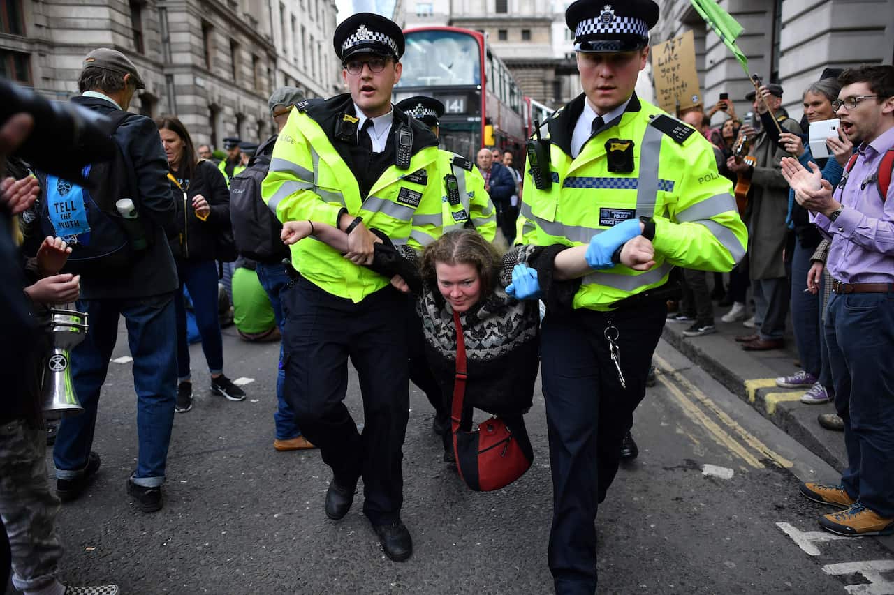 Police officers remove climate change activists from their road blockades around the Bank of England in the City of London financial district.