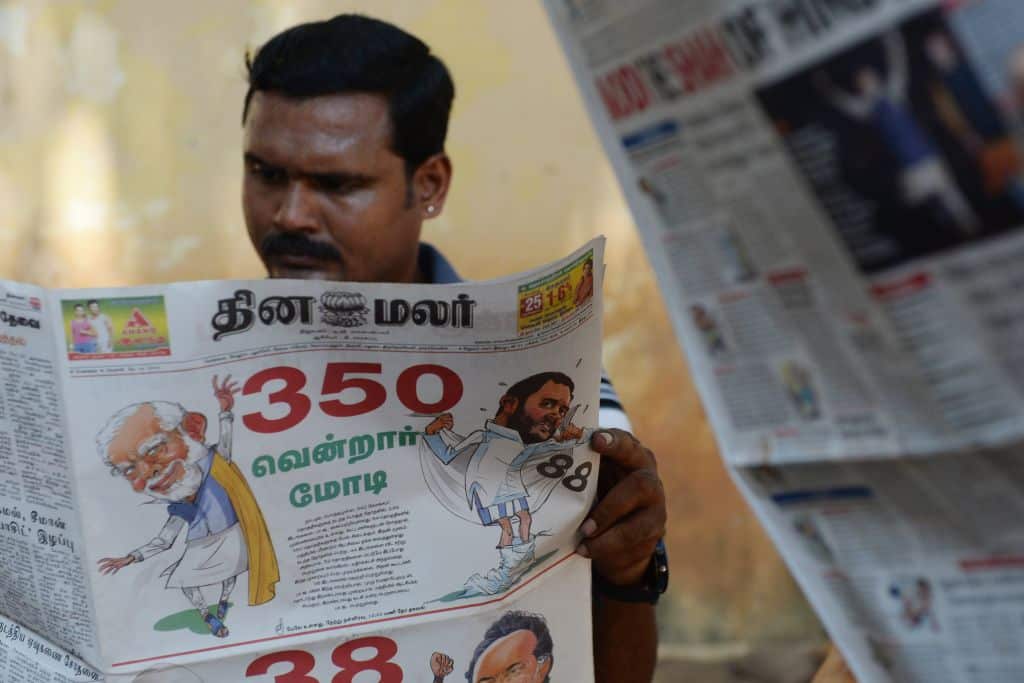 An Indian resident reads a newspaper with news of the election victory of Nadendra Modi.
