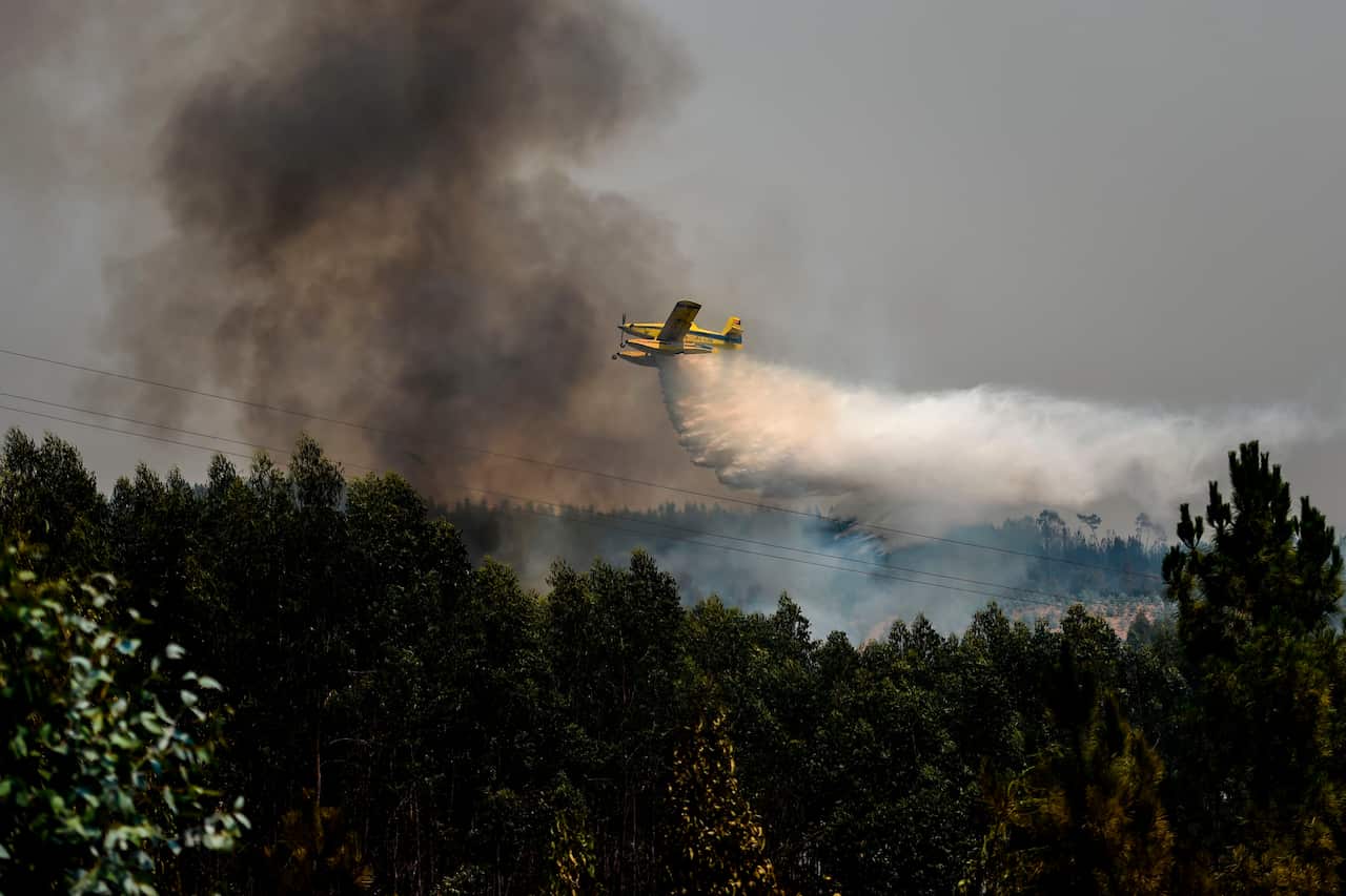 A firefighter plane drops water over a wildfire in Amendoa, Macao, in central Portugal.