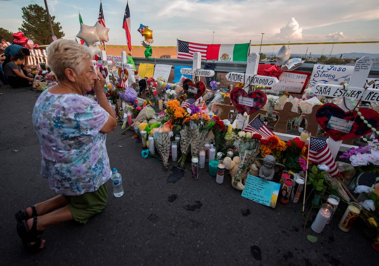 A woman prays at a makeshift memorial for victims of the Walmart shooting.