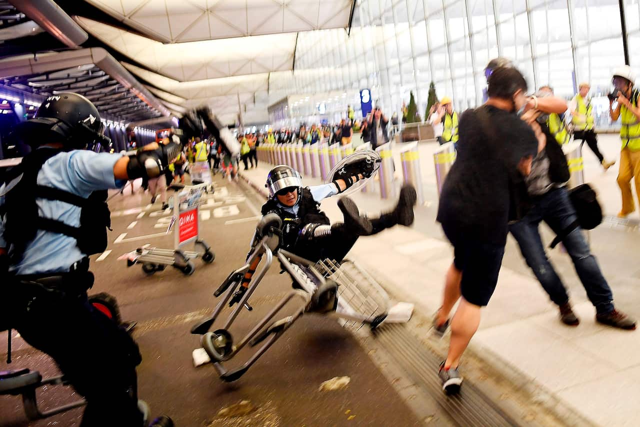 A Hong Kong policeman falls backwards as they scuffle with pro-democracy protesters during ongoing demonstrations at Hong Kong's International Airport.