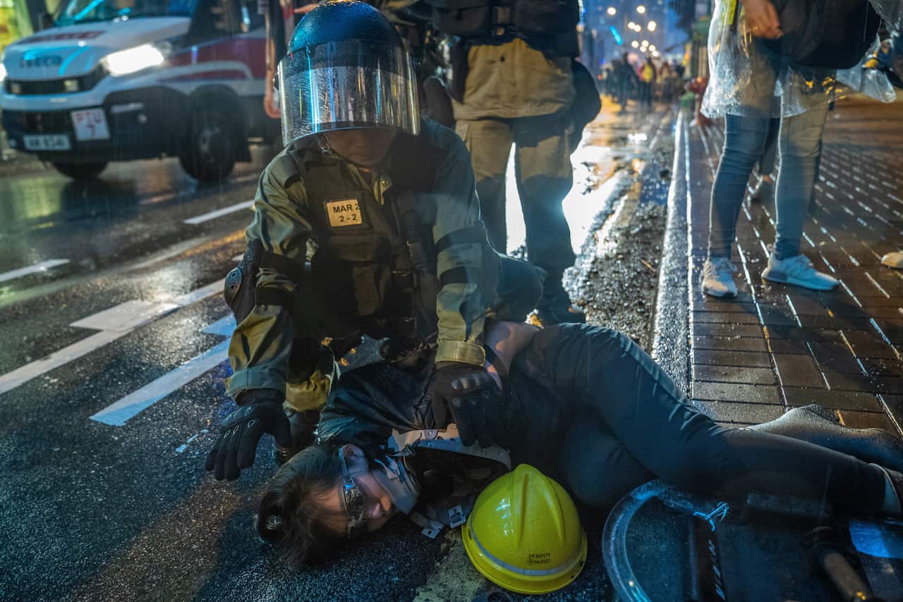 A female protester arrested by a riot police officer during demonstrations in Hong Kong.