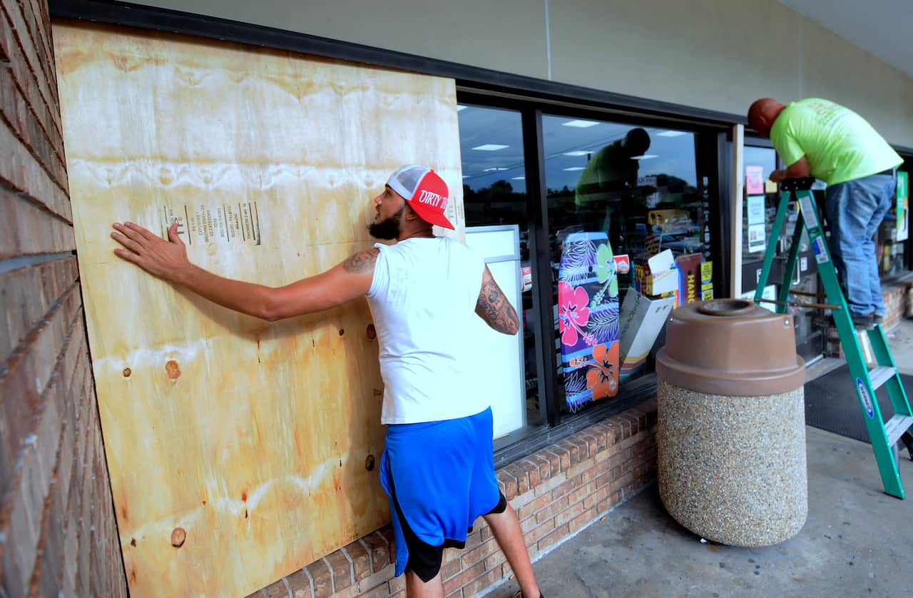 Workers install protective sheets of plywood over the windows of a convenience store in preparation for the arrival of Hurricane Dorian.