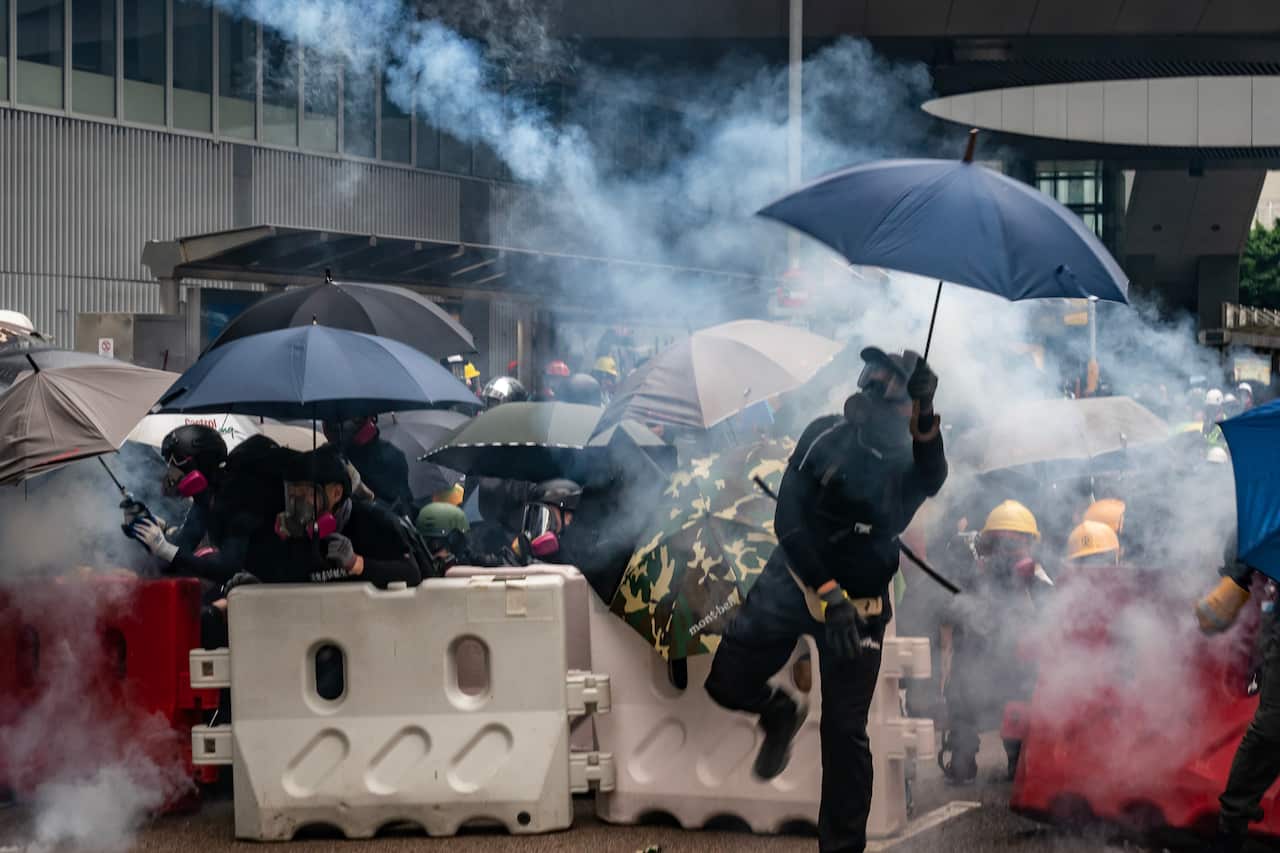 Protesters throw tear gas canisters back at police during an anti-government rally outside of Central Government Complex.