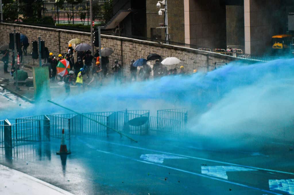 Police fire a water cannon filled with blue dye at protesters outside the government headquarters in Hong Kong.