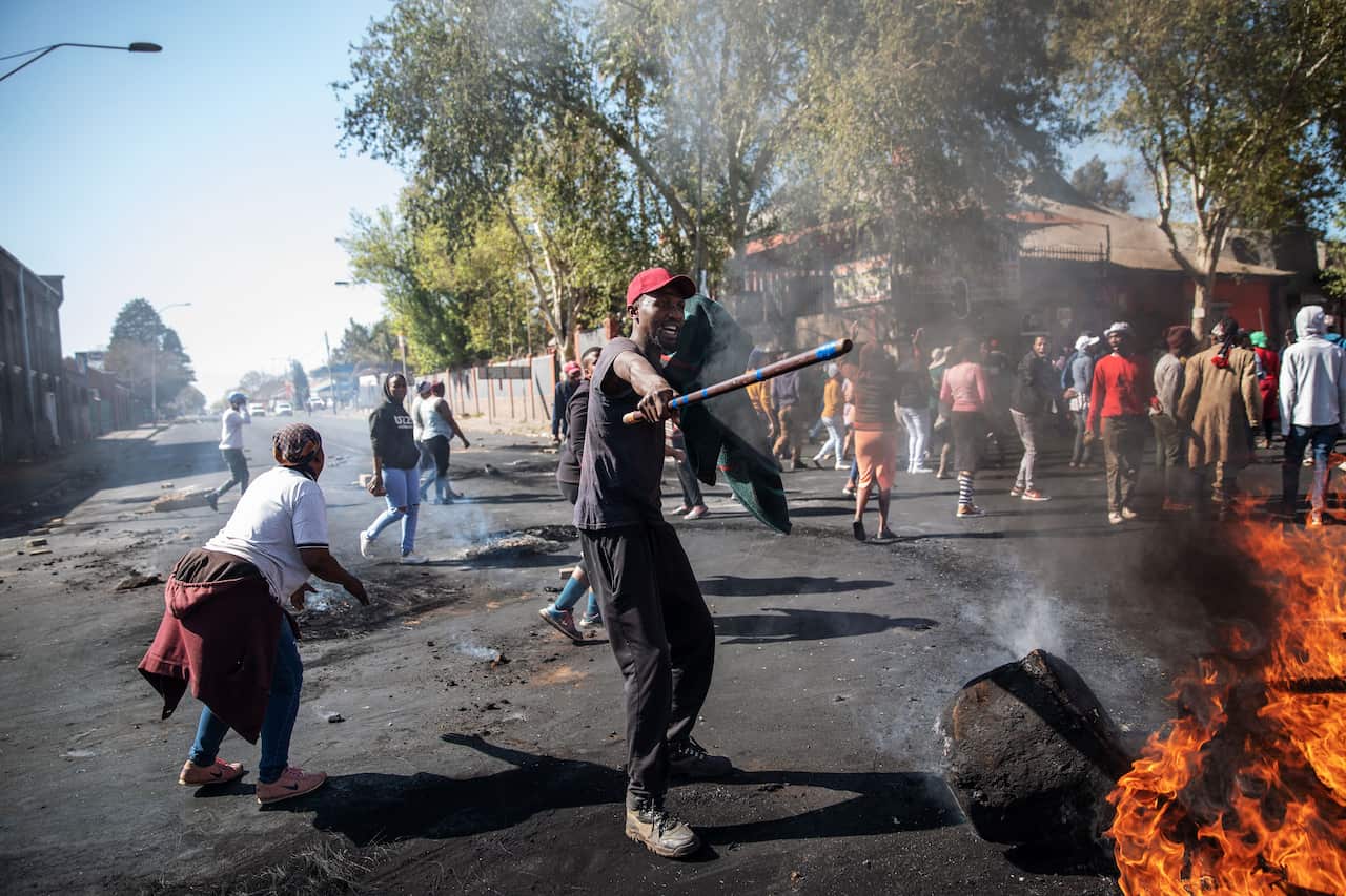 A man waves a stick in front a burning piece of furniture during a riot in the Johannesburg suburb of Turffontein on September 2, 2019