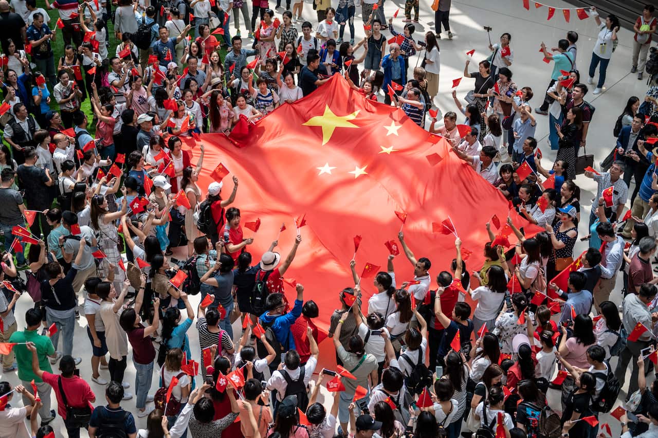 Pro-Beijing protesters are seen waving a large Chinese flag inside a shopping mall in Hong Kong.