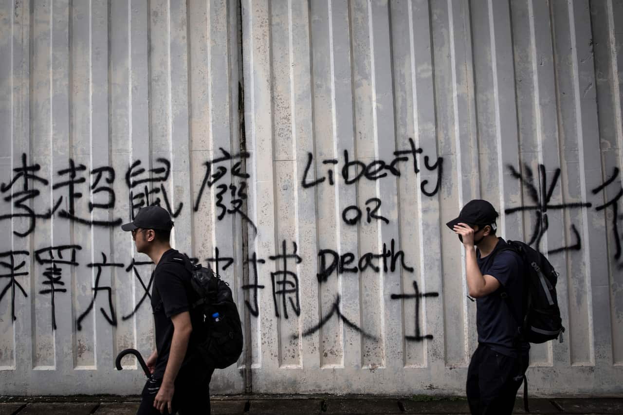 Pro-democracy protesters walk past graffiti during a march in the Hung Hom neighborhood.