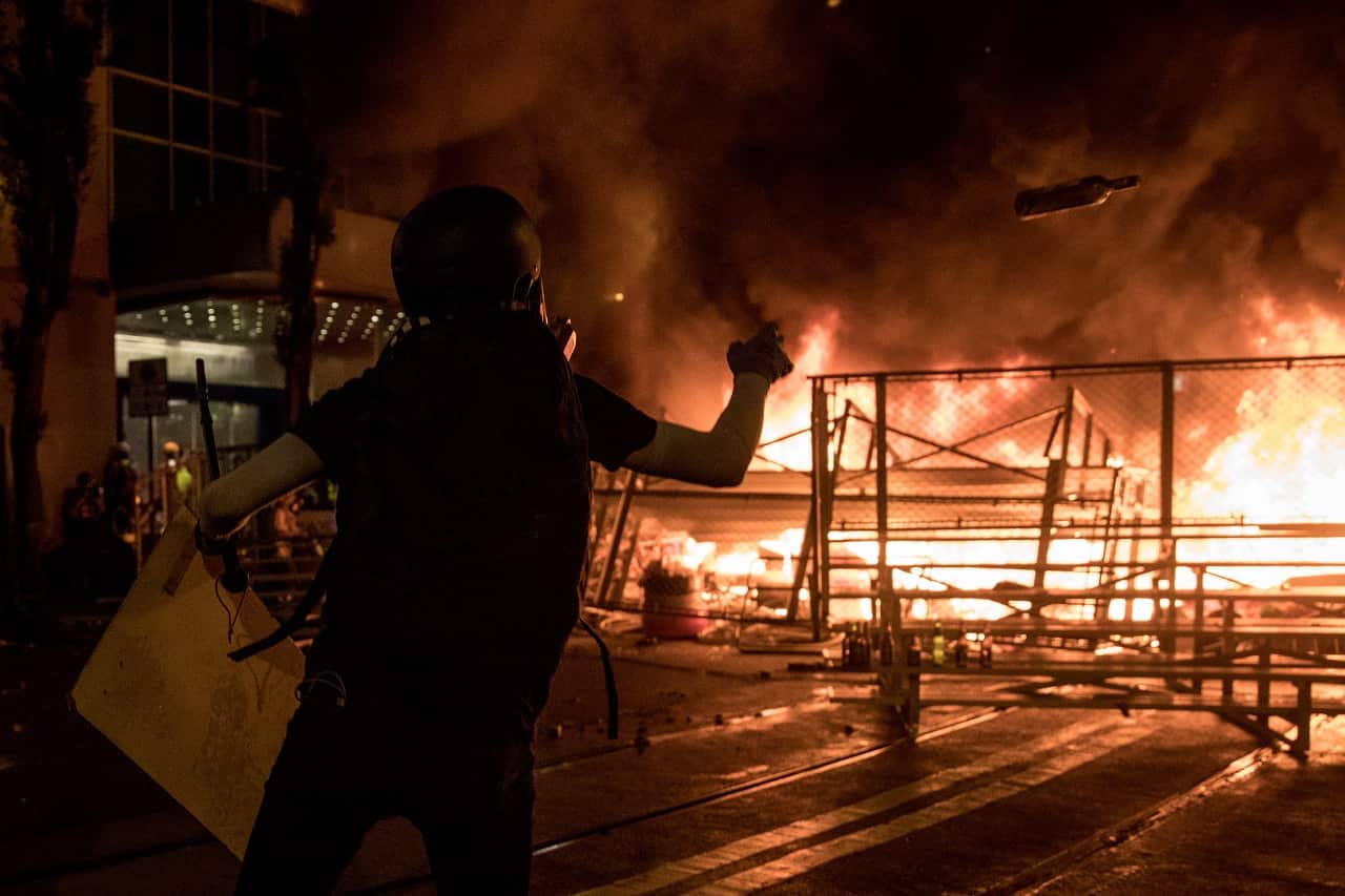 A protesters throws a bottle onto a burning barricade in Hong Kong on Saturday.