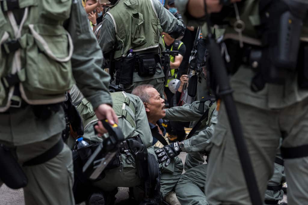 A man shouts out as he's held down by the riot police during