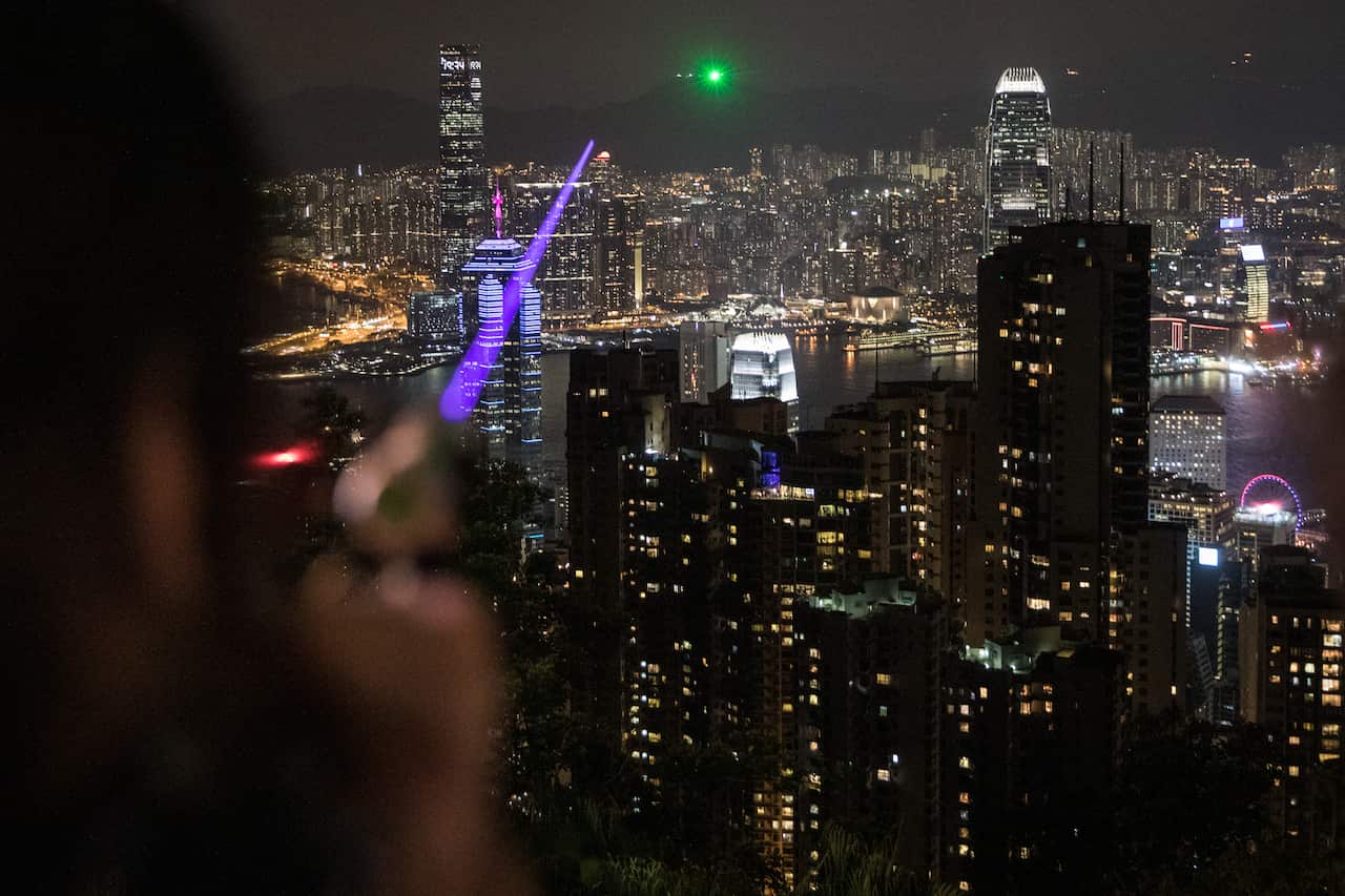 A pro-democracy protester points a high powered laser pointer at other protesters who had gathered on Lion Rock.