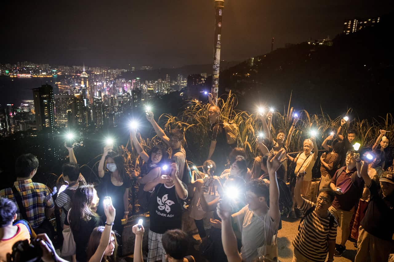 Pro-democracy protesters form a human chain and wave laser pointers, phones and lanterns in the air on Victoria Peak.