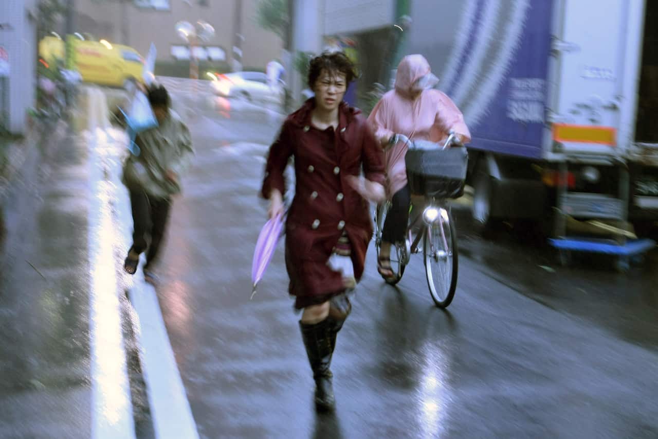 A passerby using an umbrella struggles against a heavy rain and wind as Typhoon Hagibis approaches Japan's mainland.