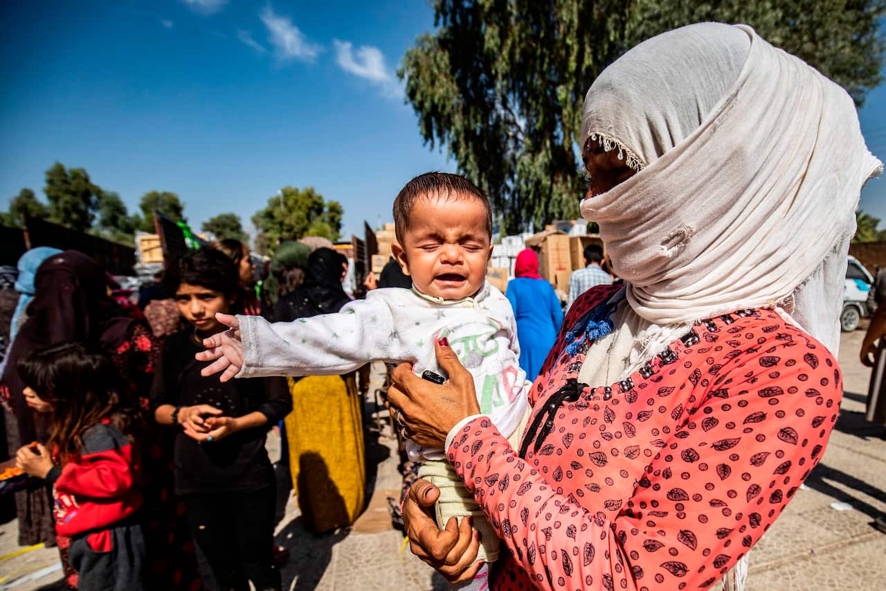 Displaced Syrians, who fled their homes in the border town of Ras al-Ain, receive humanitarian aid in the town of Tal Tamr.