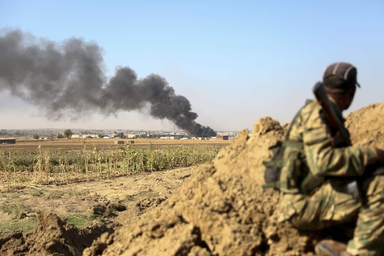 Turkish-backed Syrian rebels watch as smoke billows from the border town of Ras al-Ain.