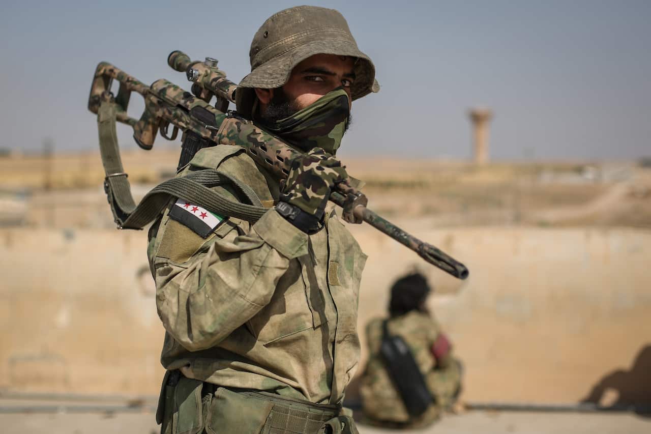 A sniper from the Turkish-backed Syrian National Army satnds on a rooftop at Suluk town in the countryside of Tell Abiad after clashes with Kurdish fighters.