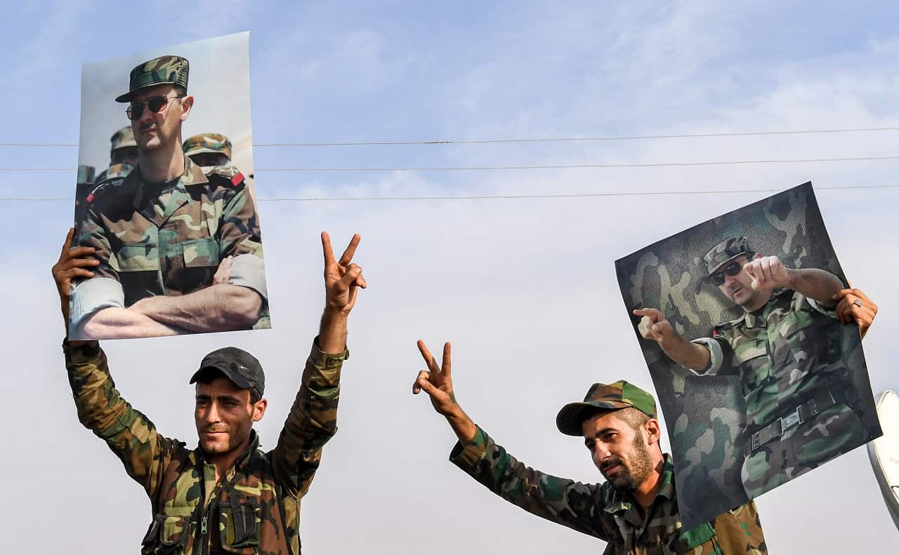 Syrian government soldiers hold up portraits of President Bashar al-Assad earlier this week.