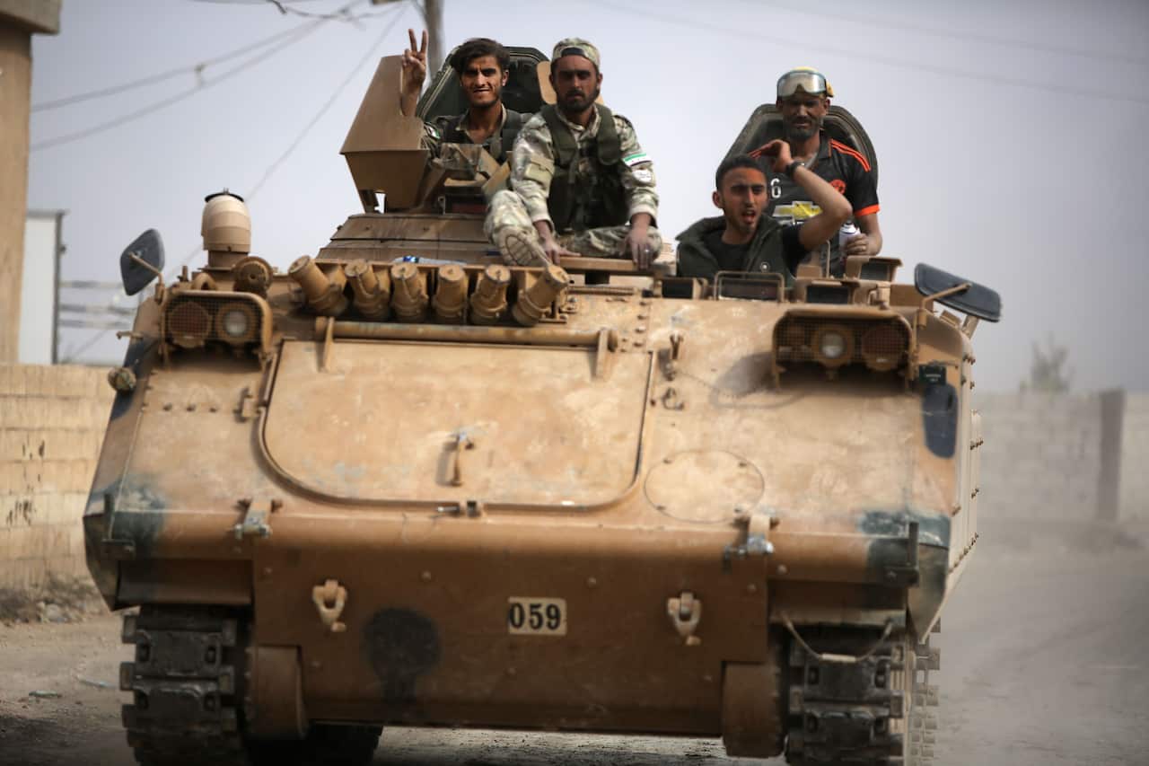 An armoured personnel carrier transports Turkey-backed Syrian fighters on the road between the Syrian towns of Tal Abyad and Kobane.