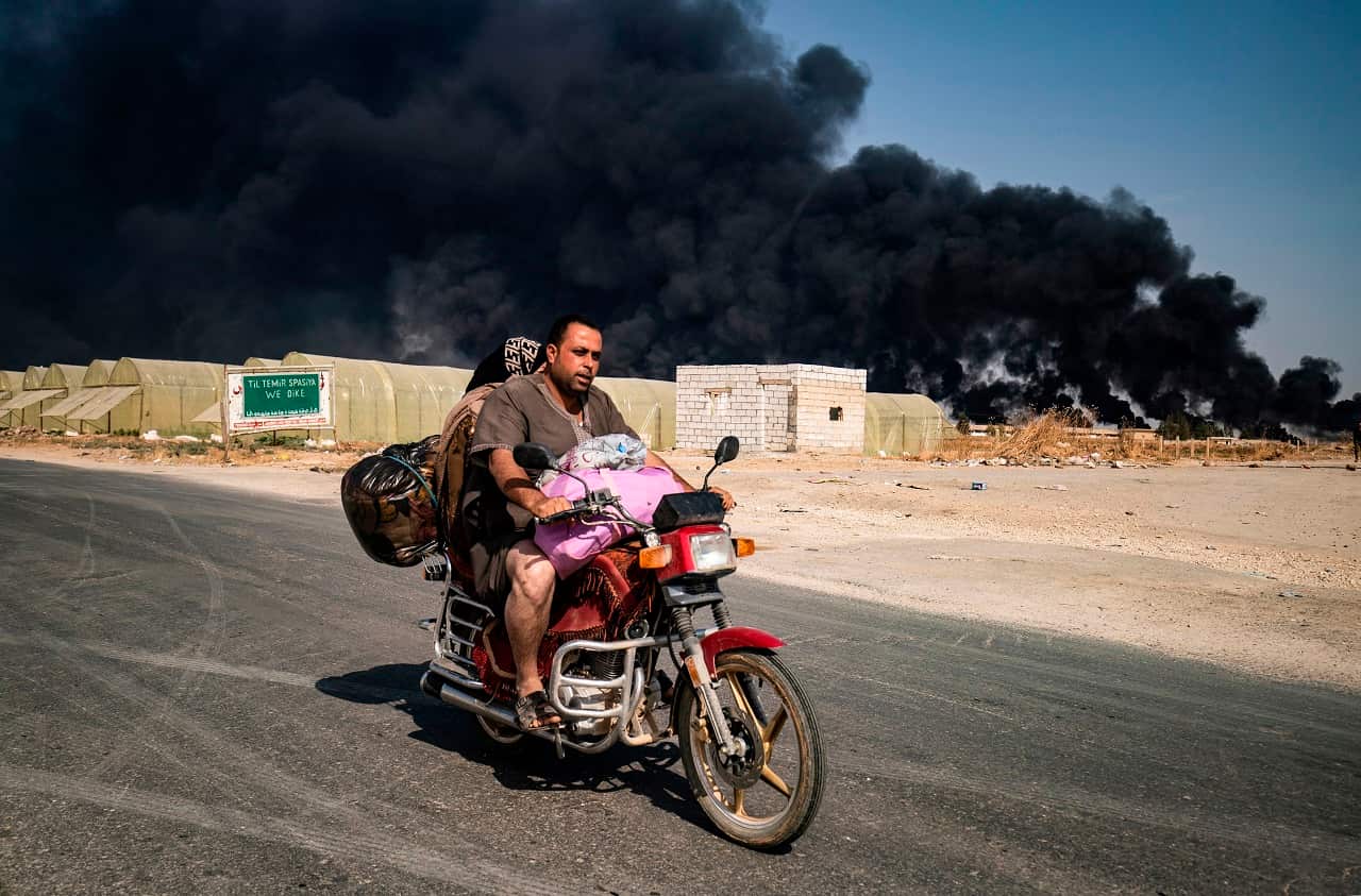 People flee from the Syrian Kurdish town of Ras al-Ayn along the border with Turkey.