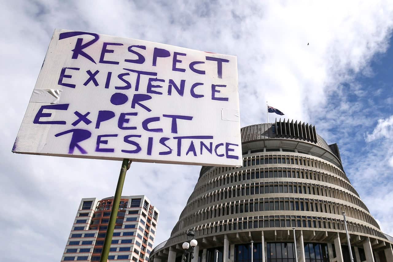 A protester holds a placard in front of New Zealand's Parliament.