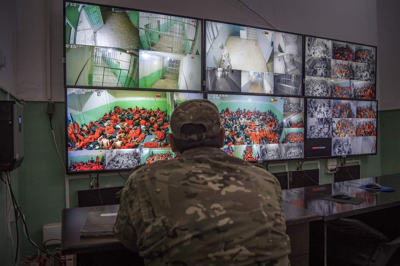 A fighter with the Syrian Democratic Forces (SDF) monitors the prison's surveillance screens. Many of the prisoners are accused of being affiliated with IS.