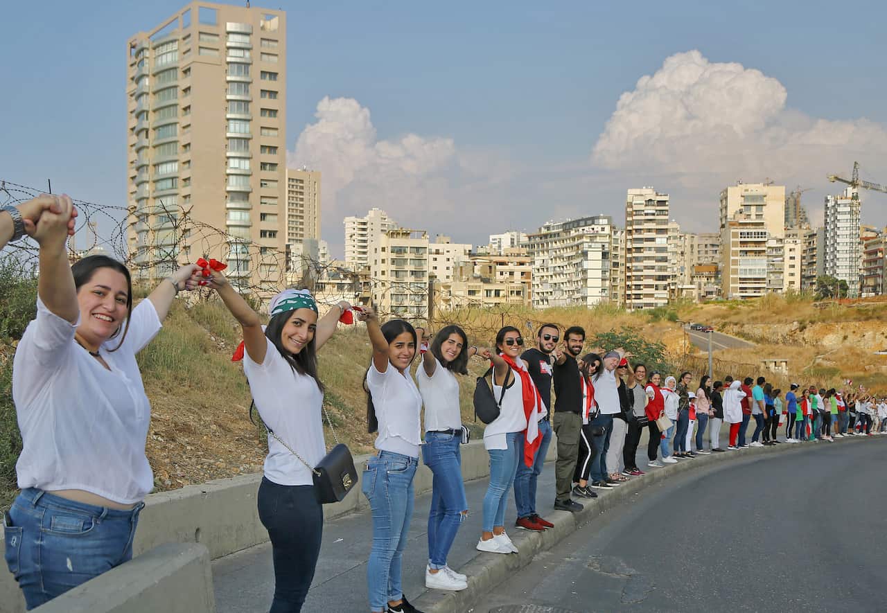 Lebanese protesters hold hands as they form a human chain stretching along the coast from the capital Beirut to northern and southern Lebanon.