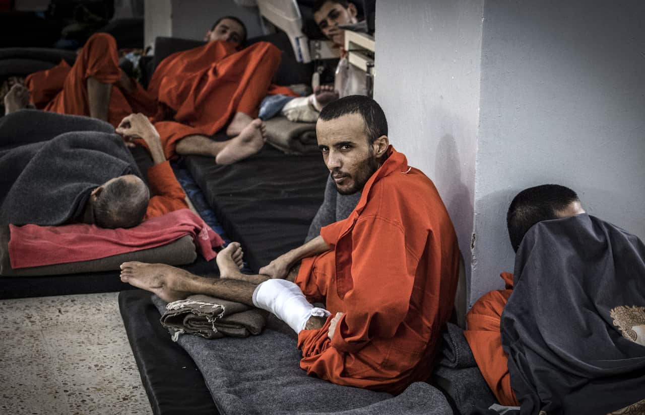 A wounded man, suspected of being affiliated with IS, sits on the floor in a prison cell in the northeastern Syrian city of Hasakeh.