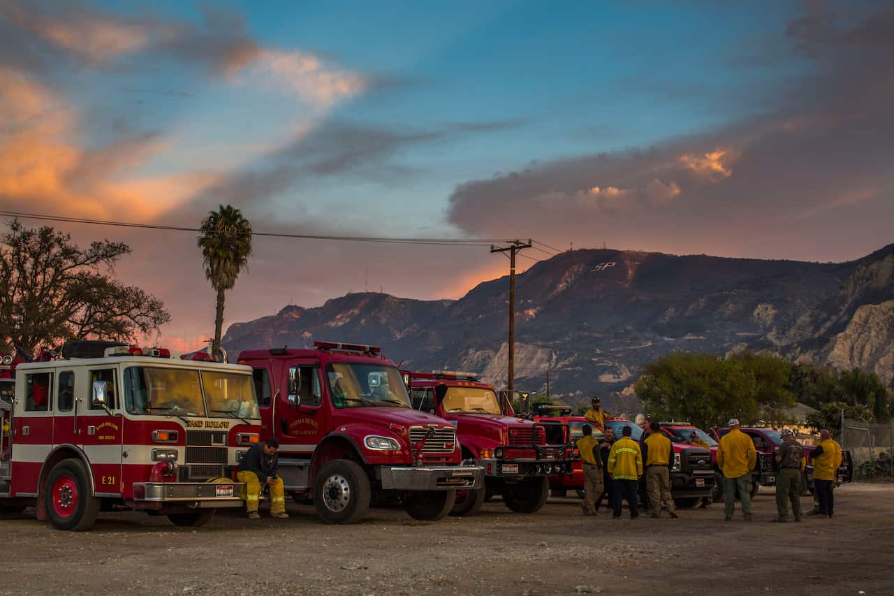Firefighters are taking a break at the end of the day in front of the scorched mountain, after the Maria Fire, in Santa Paula, Ventura County, California.