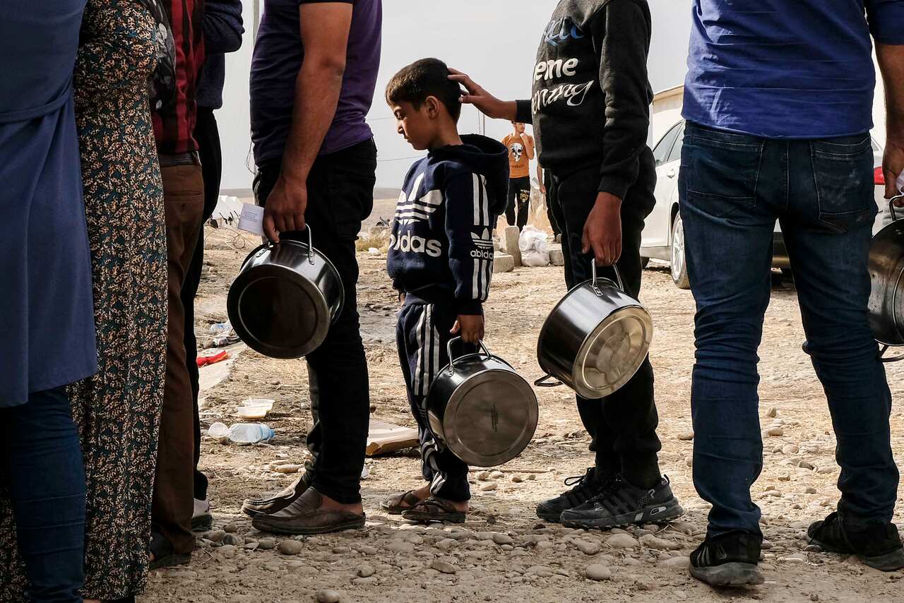 Syrian refugees fleeing the Turkish incursion in Rojava wait to receive water, bread and lentil soup at the Bardarash IDP camp in Dohuk, Iraq.