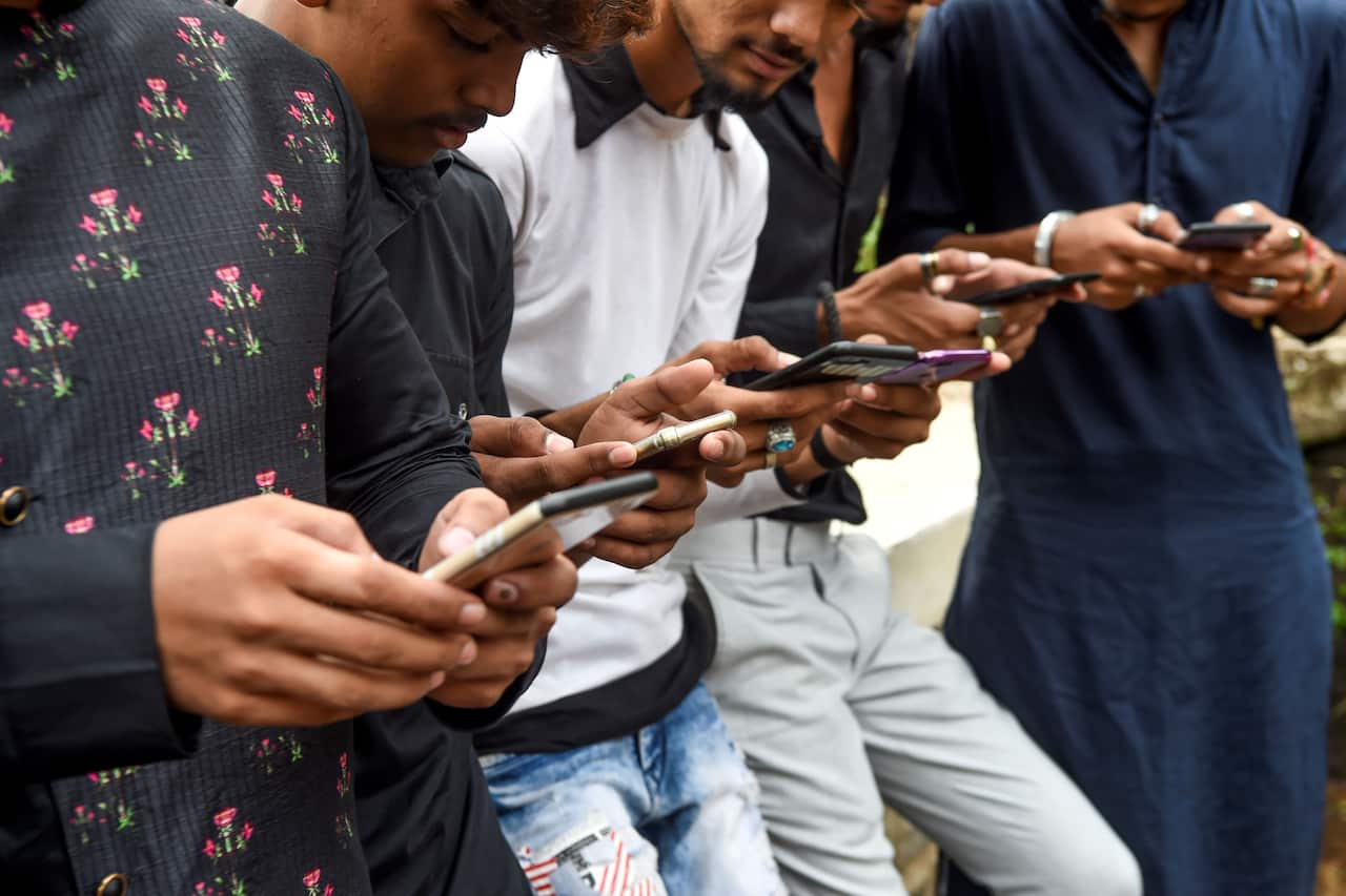 Youths watching videos on video-sharing app TikTok on their mobile phones in Mumbai.