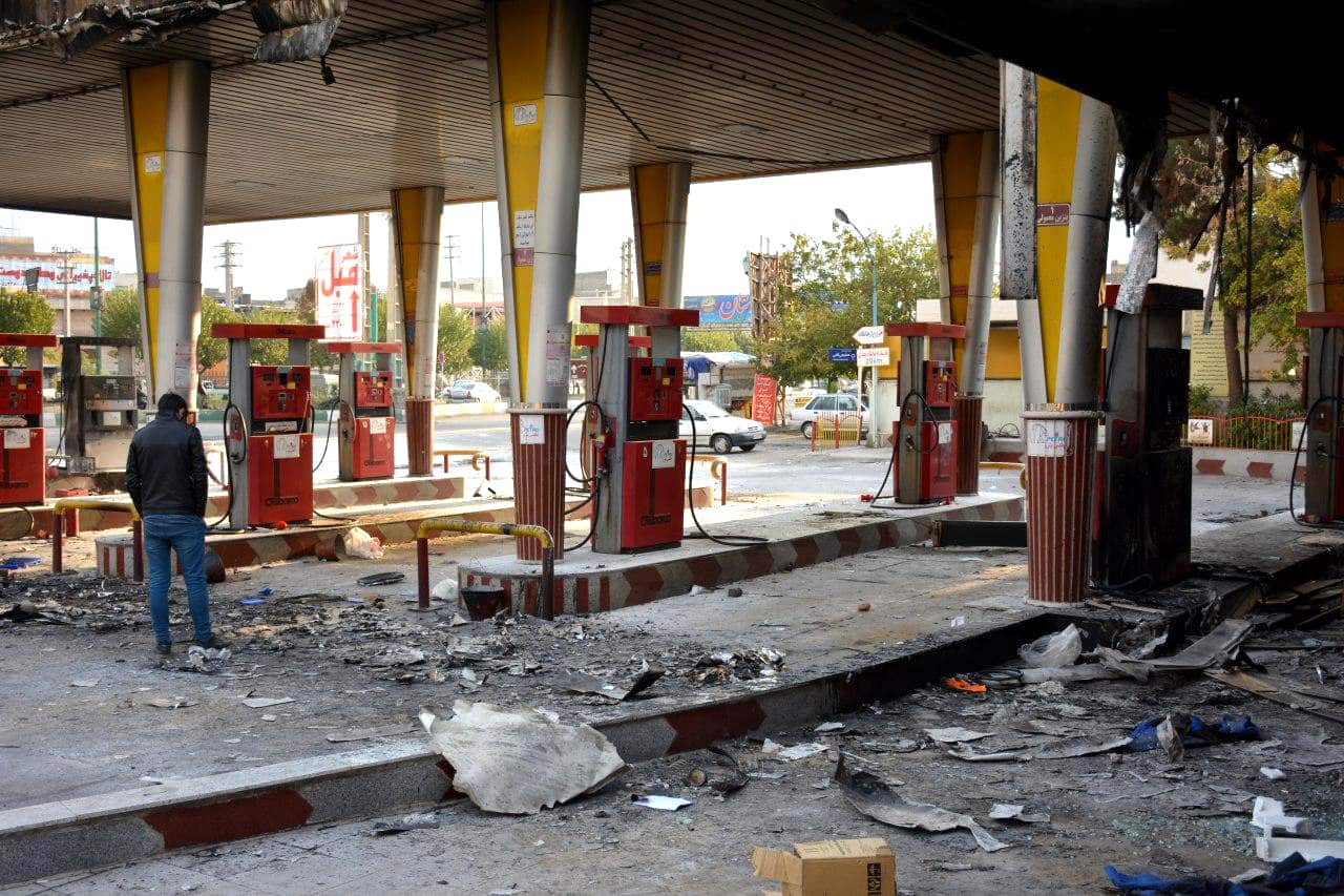 An Iranian man checks a scorched gas station that was set ablaze by protesters during a demonstration against a rise in gasoline prices.