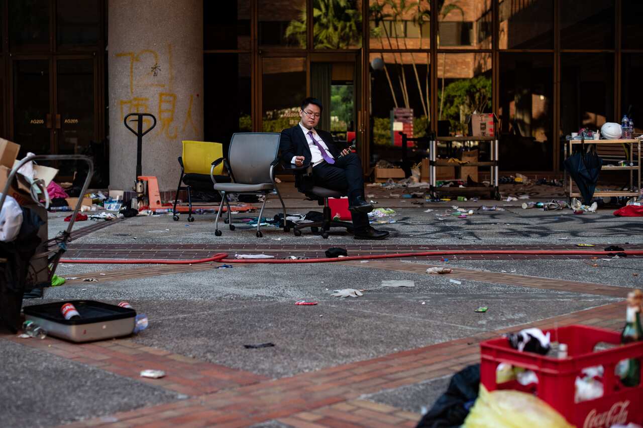 A man sits at a debris-strewn area on the Hong Kong Polytechnic University campus.