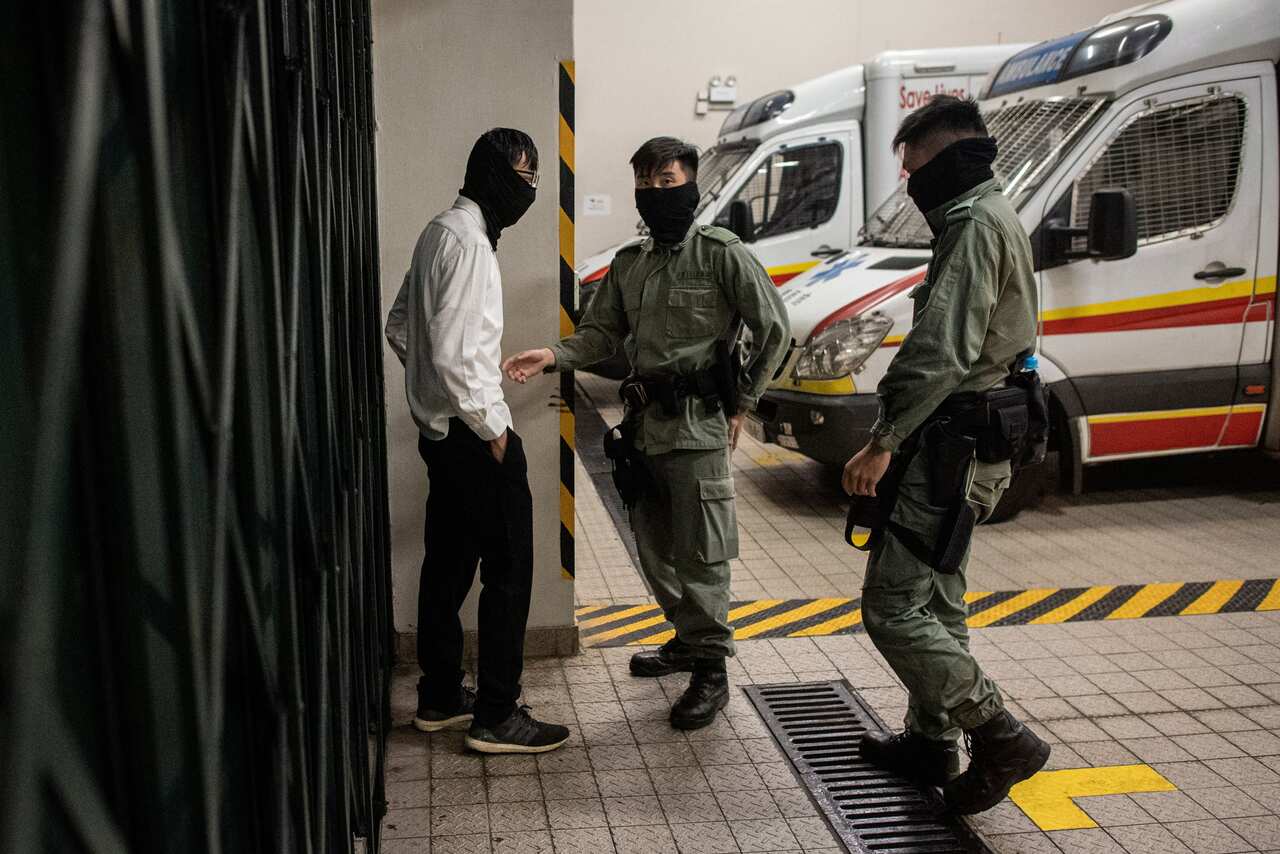 A protester (L) is checked by the police as he surrenders outside the main entrance of the campus of the Hong Kong Polytechnic University.