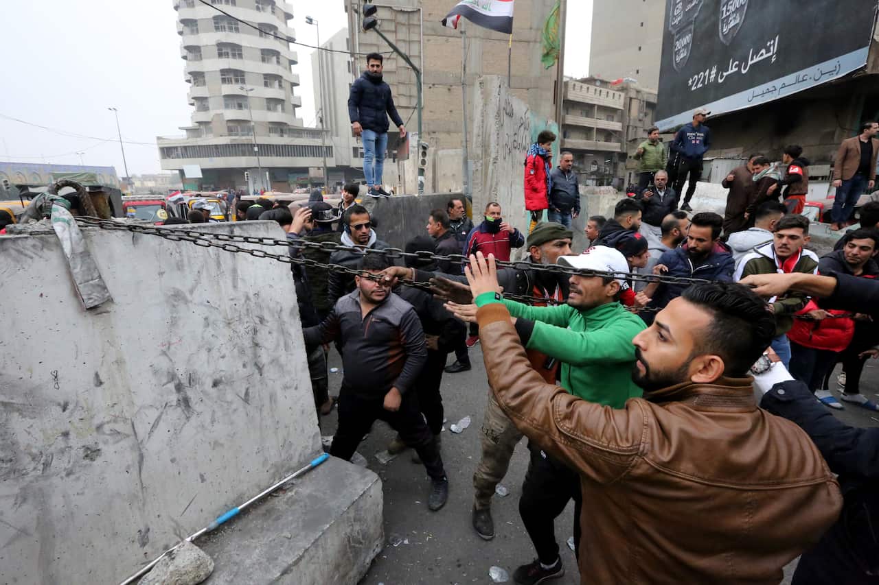 Iraqi protesters move a cement block at Al-Khilani square.