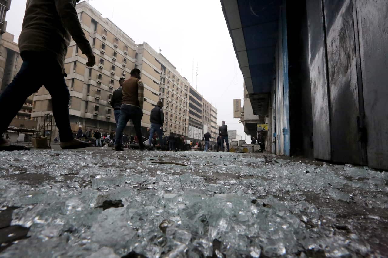 Iraqis walk by broken glass at Al-Khilani square.