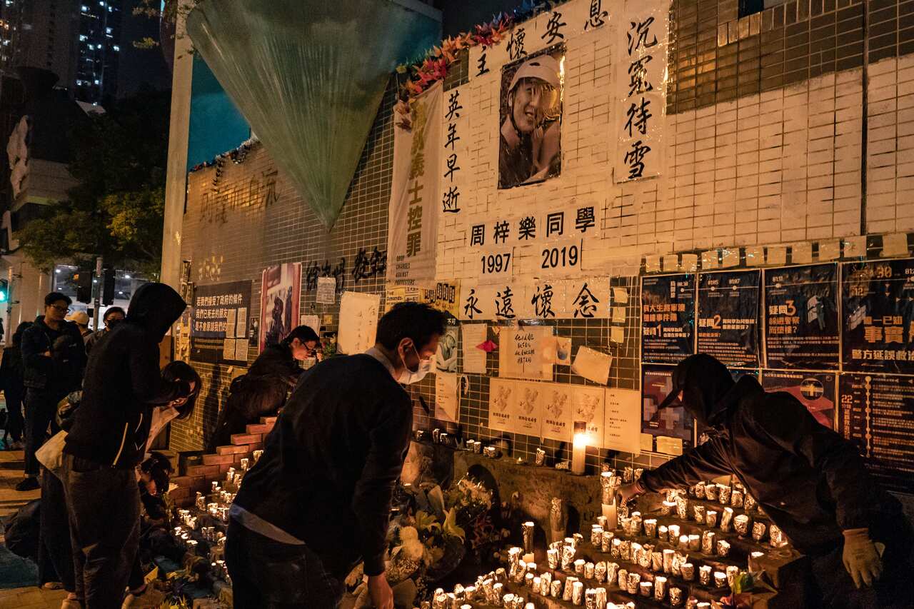 Mourners hold a candle light vigil to commemorate Alex Chow who died from a fall inside a parking ramp where police and protesters were clashing.