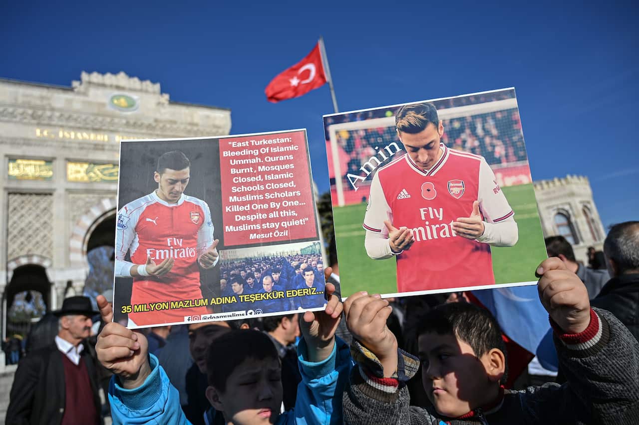 Supporters of China's Muslim Uighur minority hold placards of Arsenal's Turkish origin German midfielder Mesut Ozil.